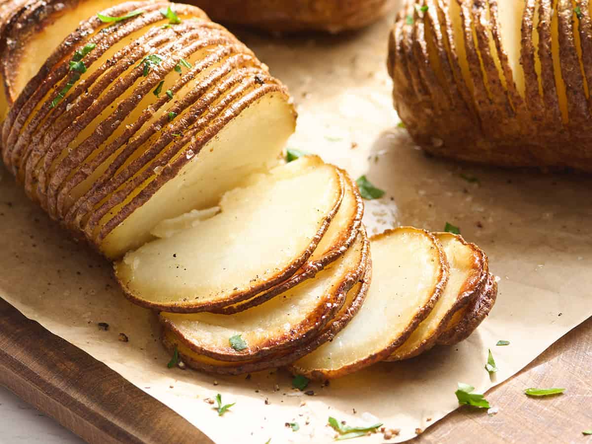Vista lateral de una patata Hasselback con las rodajas separadas.