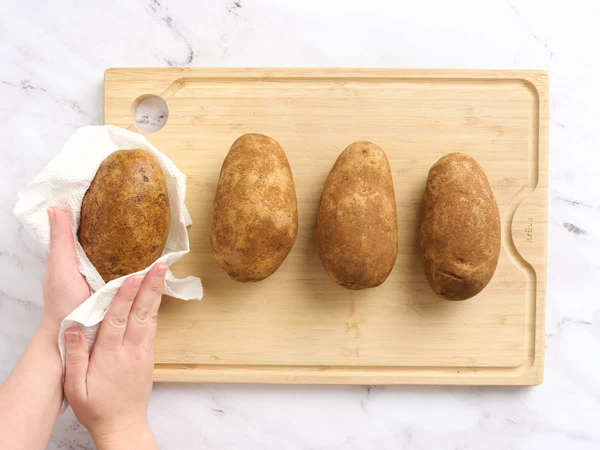 Patatas sobre una tabla de cortar se secan con una toalla de papel.