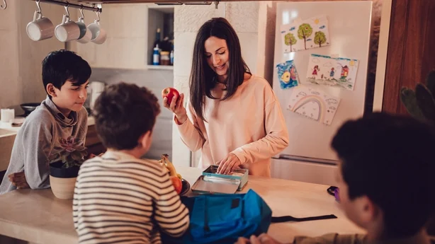 Madre preparando loncheras con comida saludable y refrigerios para sus hijos antes de ir a la escuela