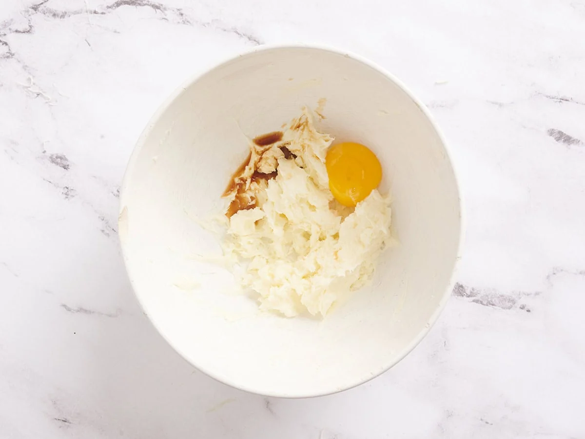 Se agrega una yema de huevo a la mezcla de tarta de queso para las barras de pastel de zanahoria.