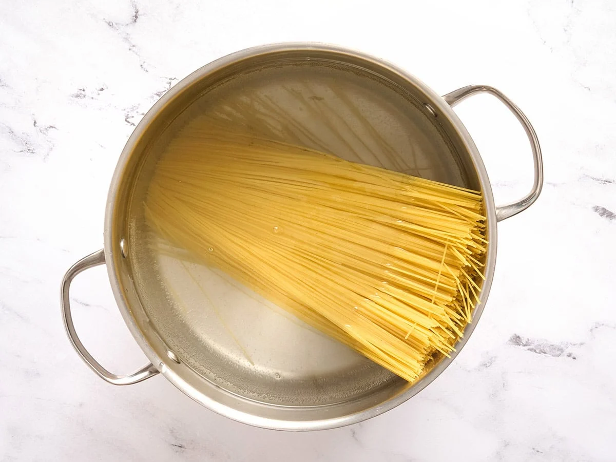 Pasta de cabello de ángel añadida a una olla con agua.