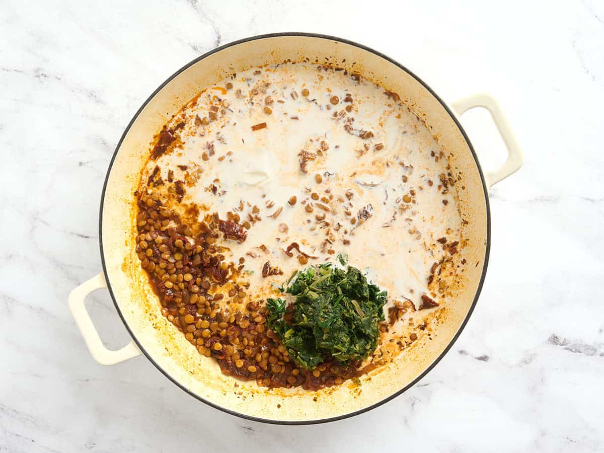 Crema y espinacas congeladas agregadas a una olla para casarme con lentejas.