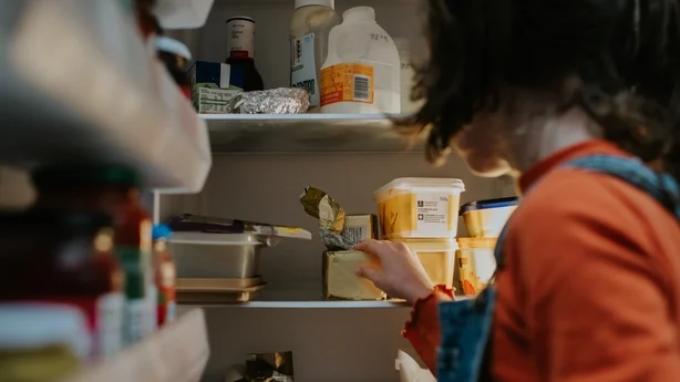 Un niño abre un refrigerador y mete la mano en su interior.