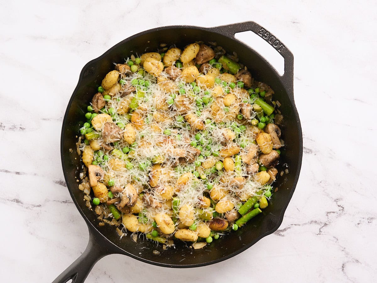 Ñoquis de verduras terminados con queso parmesano encima.