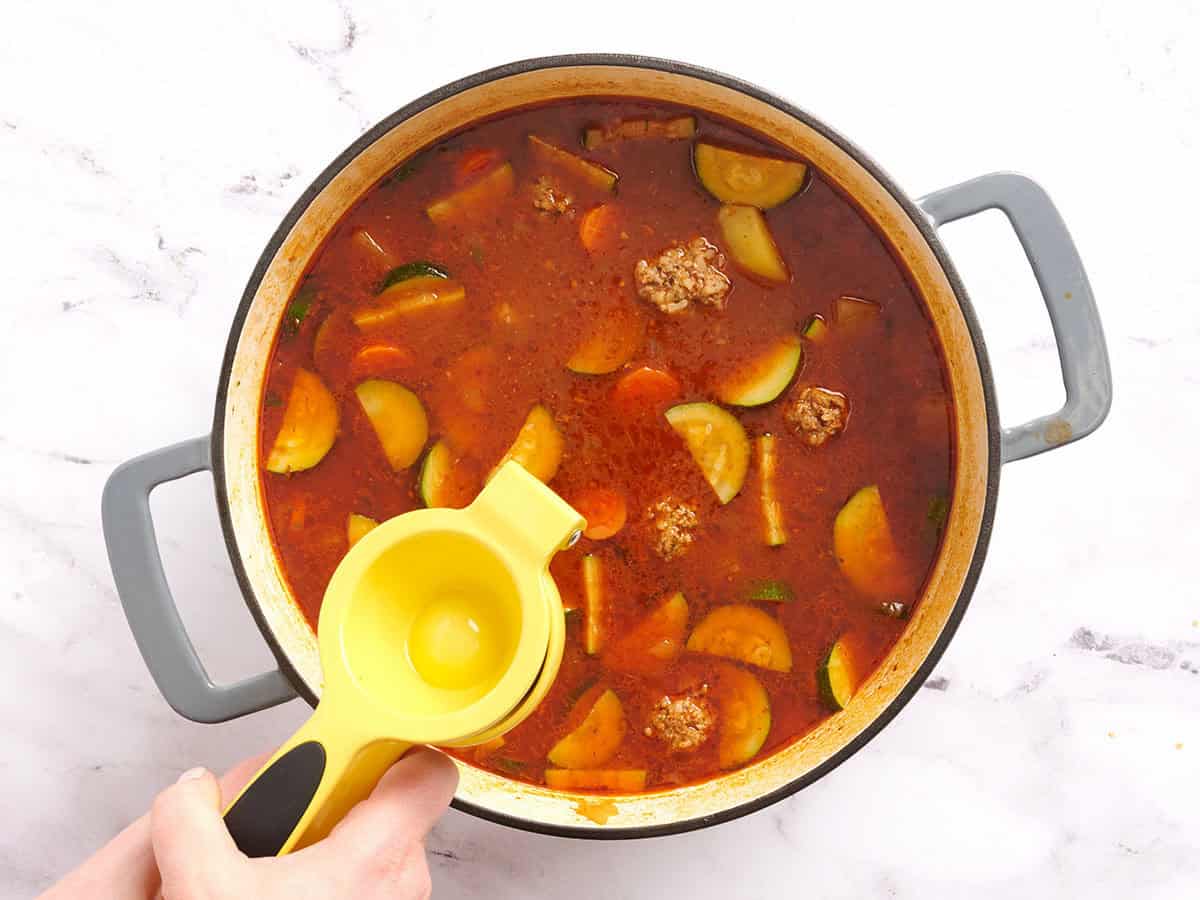 Se exprime media lima fresca en una olla de sopa de albóndigas mexicana.