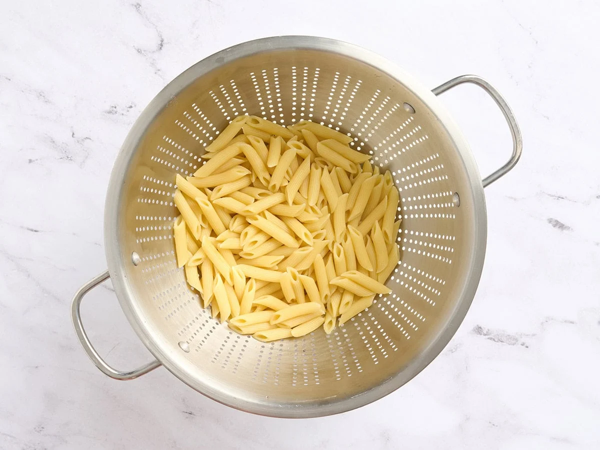 Pasta penne cocida en un colador.