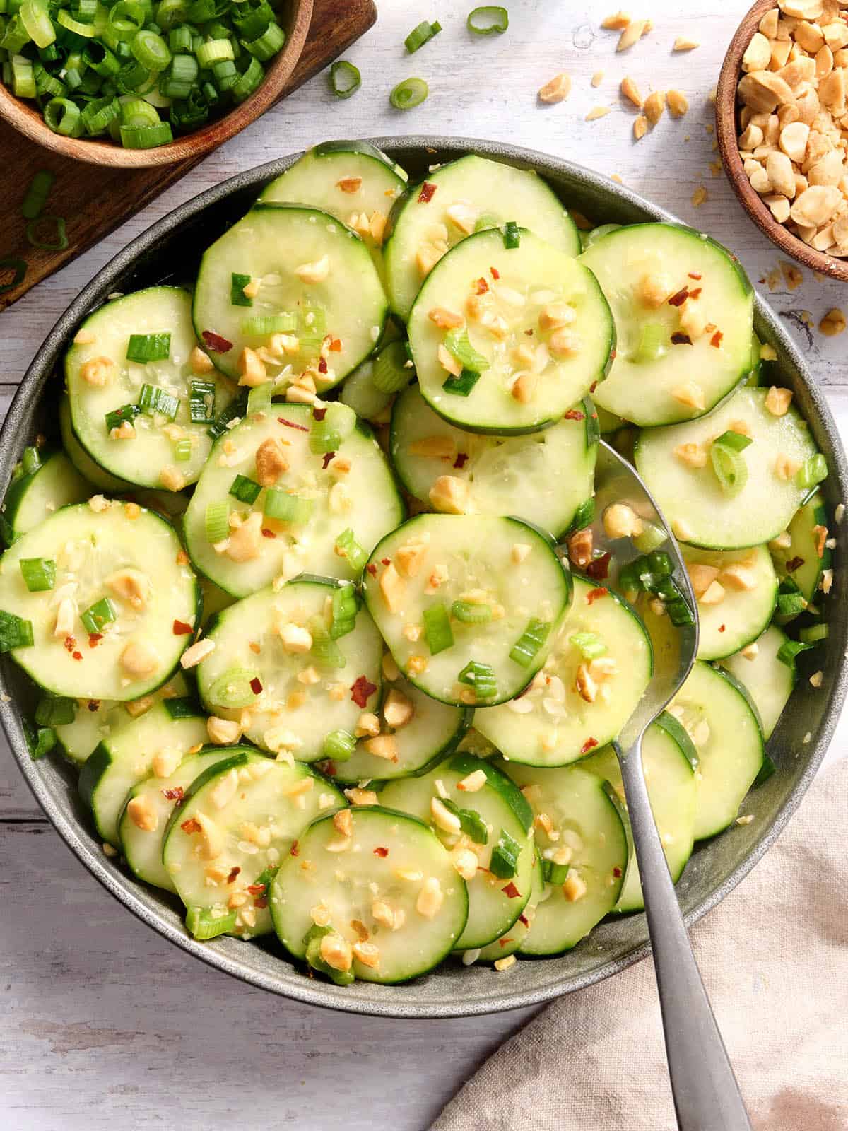 Vista aérea de un plato de ensalada de pepino y sésamo con una cuchara.