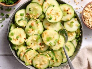 Overhead view of a bowl of sesame cucumber salad with a spoon.
