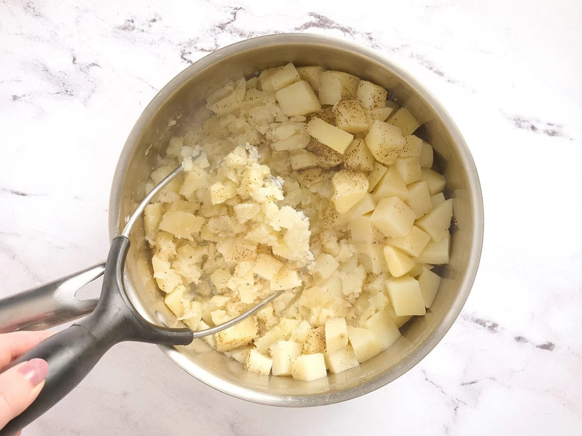 Un puré de patatas triturado en una olla.