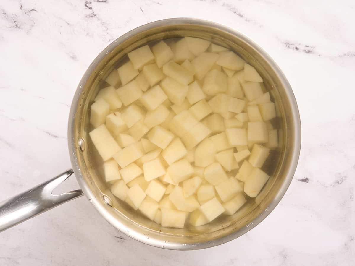 Patatas cortadas en cubitos en una olla con agua.