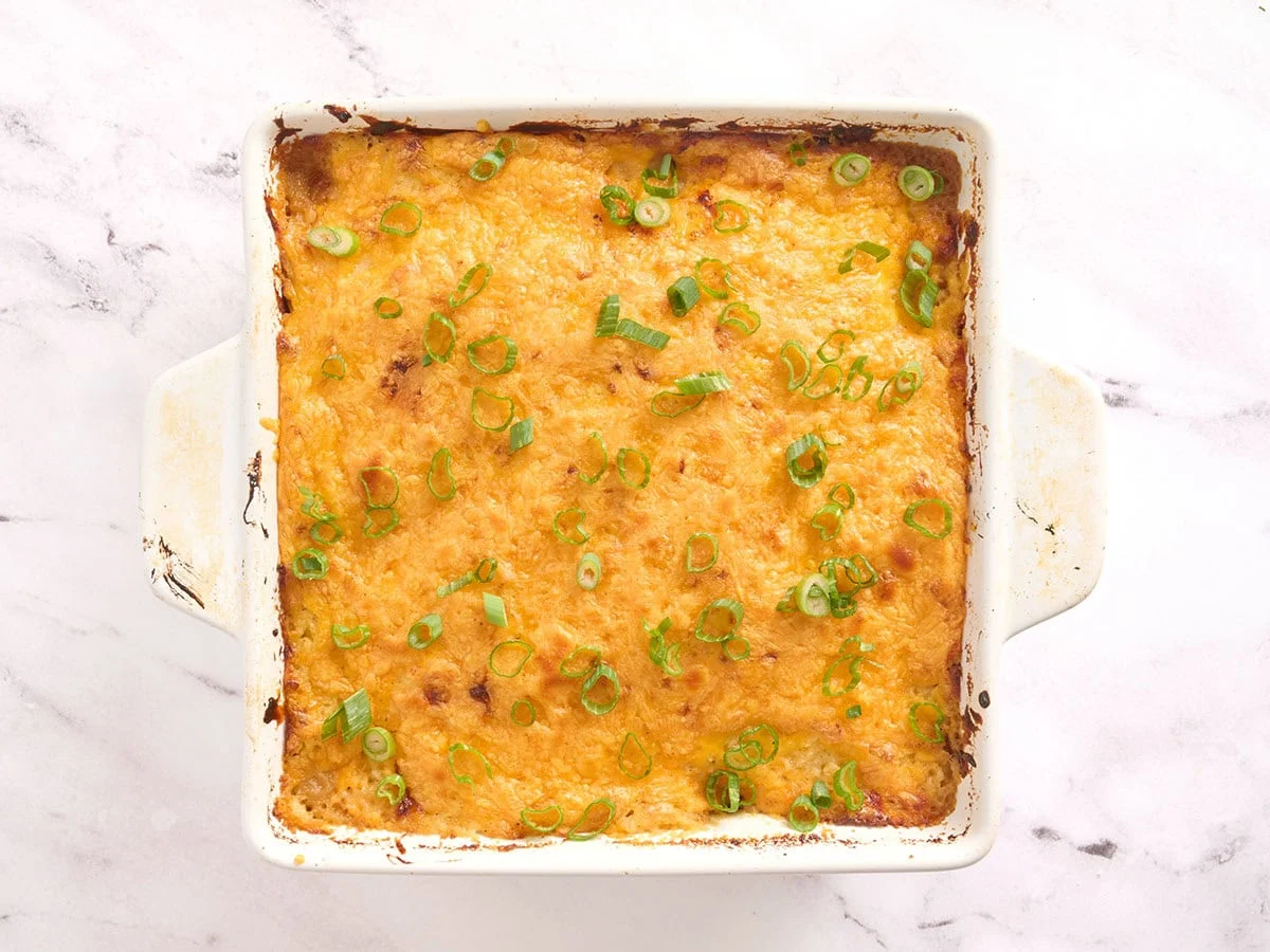 Cazuela de pastel de carne después de hornearse en el horno, cubierta con queso derretido y cebollas verdes en rodajas.
