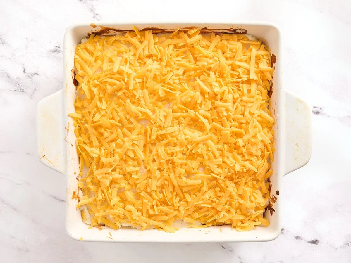 Una cazuela de pastel de carne cubierta con queso cheddar rallado.