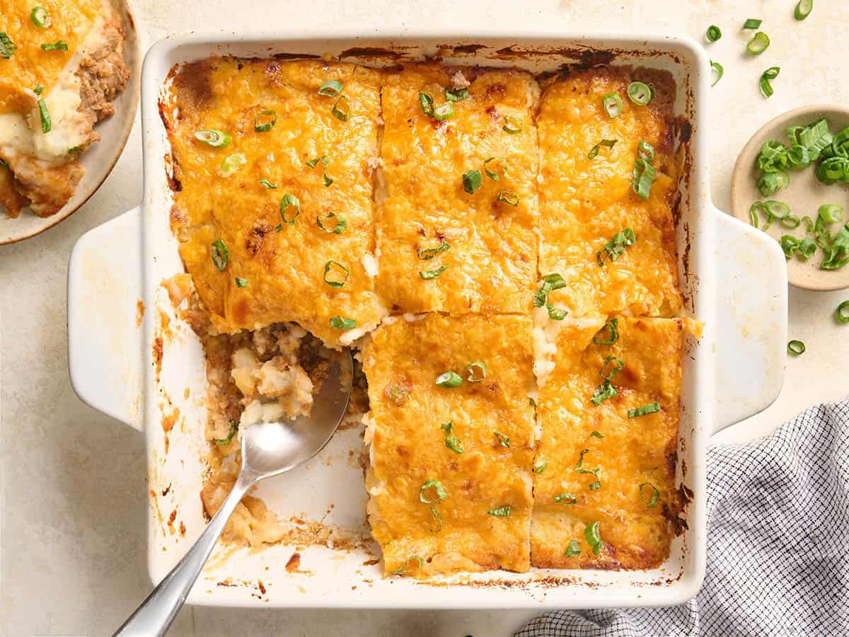 Una cazuela de pastel de carne cortada en 6 rebanadas, a la que le falta un trozo.