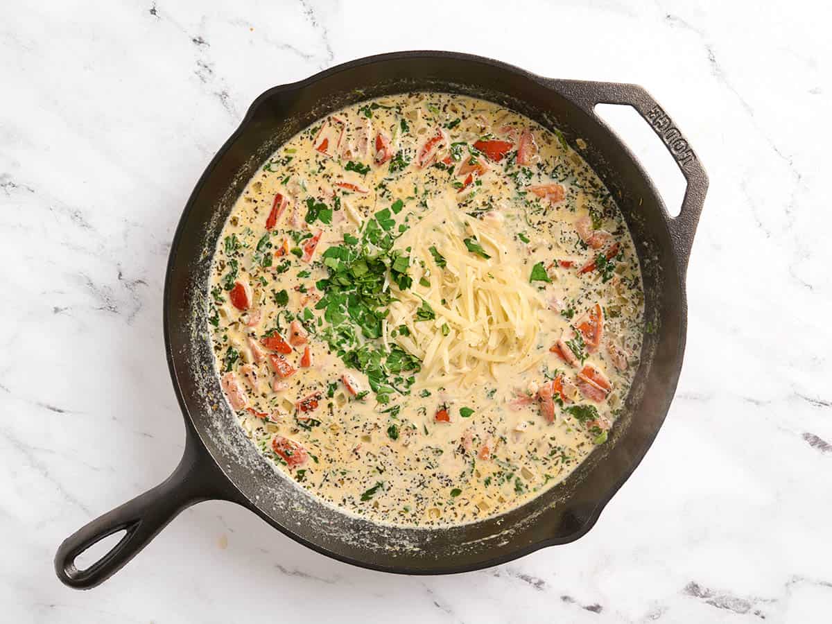 Perejil y parmesano añadidos a una sartén de salmón toscano.