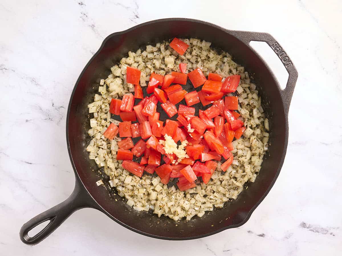 Los tomates se añaden a una sartén con el ajo y la cebolla.