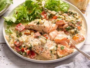 Side view of Tuscan salmon on a plate with salad.