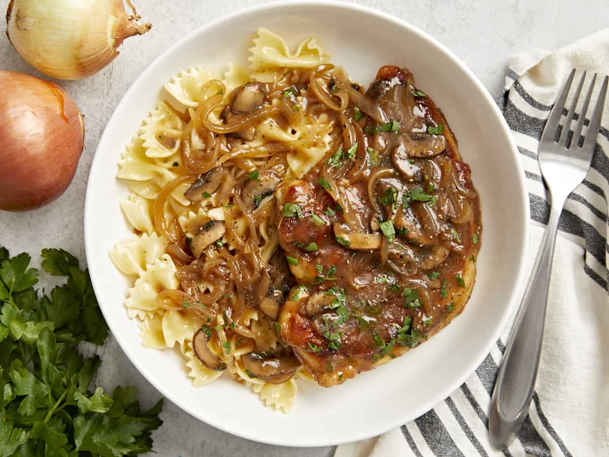 vista aérea de pollo marsala en un plato blanco con pasta de pajarita.