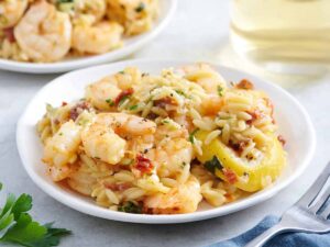 Side view of a plate of garlic shrimp and orzo.