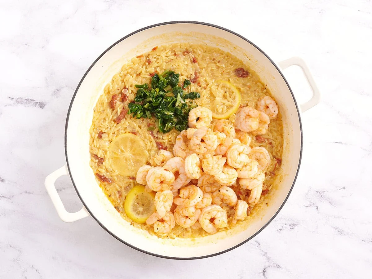Camarones y perejil en una sartén con orzo.