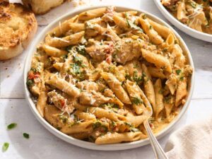 Overhead side view of marry me chicken pasta in a bowl with a fork.