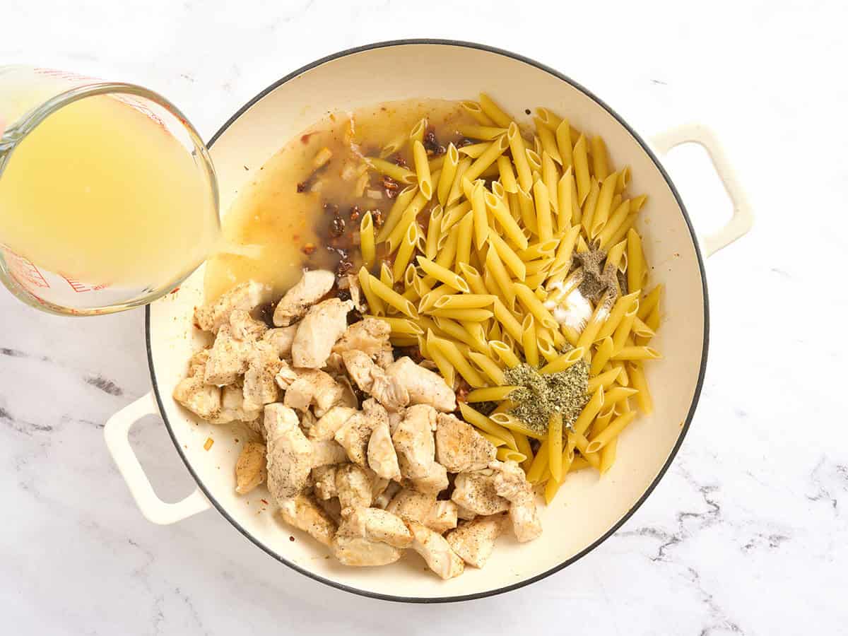 Pollo, caldo y pasta agregados a una olla con cebollas salteadas.