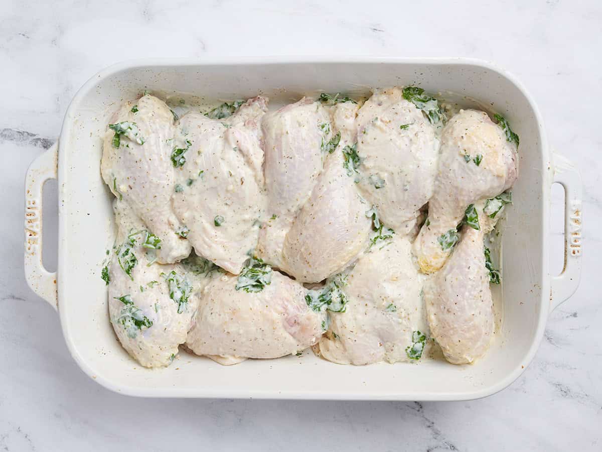 Trozos de pollo marinados en una fuente para horno.