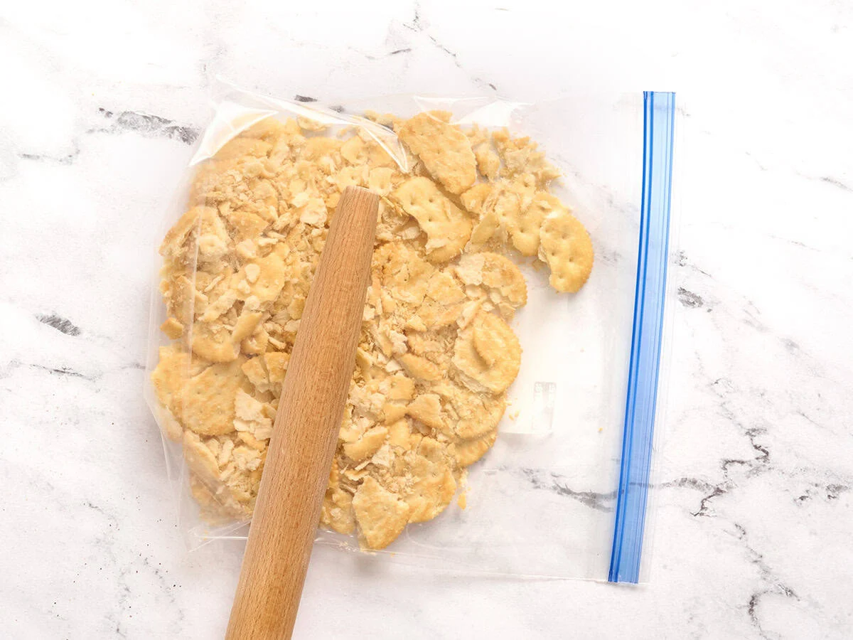 Galletas saladas en una bolsa con cierre que se trituran con un rodillo.
