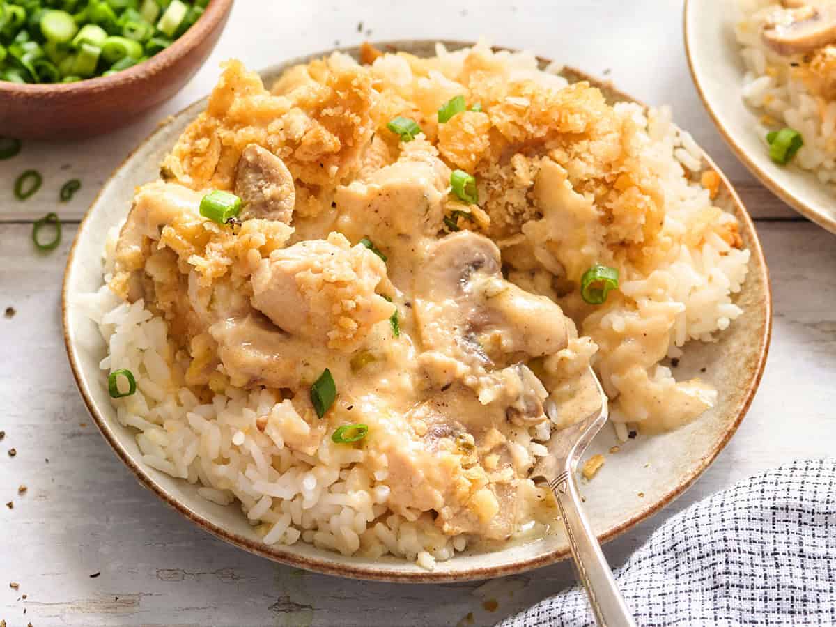 Vista lateral de una cazuela de pollo de un millón de dólares en un plato con arroz.