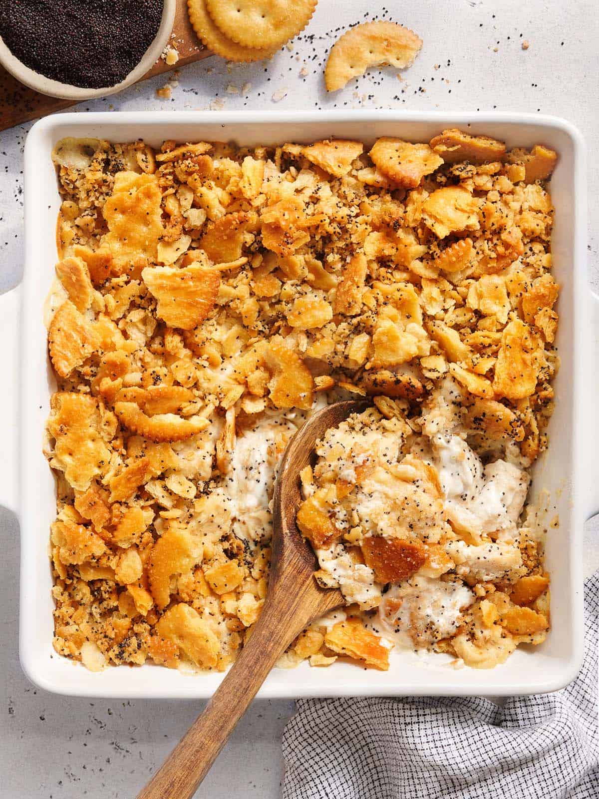 Vista aérea de una cazuela de pollo con semillas de amapola con una cuchara de madera.