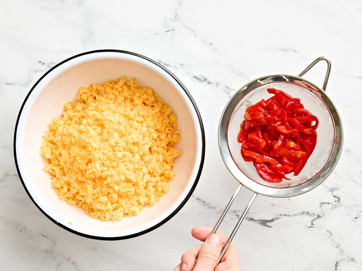 Un plato de queso cheddar rallado y pimientos escurridos.