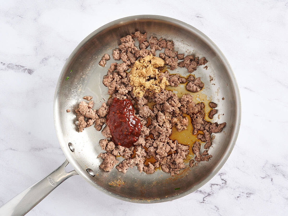 Carne molida dorada en una sartén con salsa de chile y azúcar moreno.