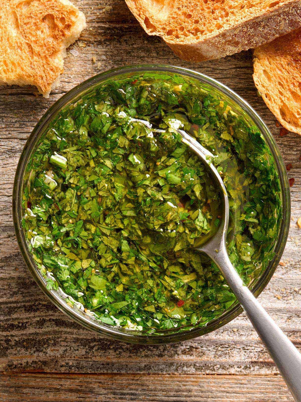 Vista aérea de un plato de salsa chimichurri con una cuchara.