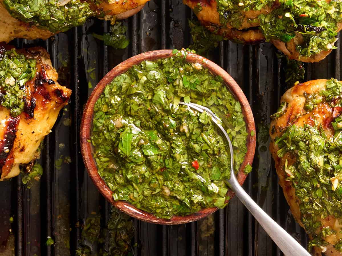 Vista aérea de un plato de chimichurri a la parrilla con un poon y muslos de pollo a la parrilla.