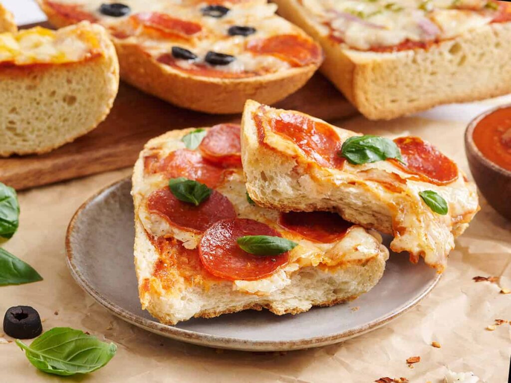 Side view of a pepperoni French bread pizza sliced in half.