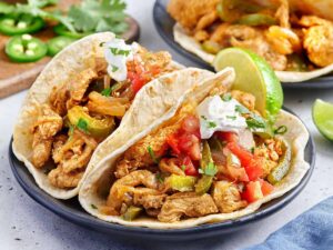 Side view of stovetop chicken fajitas with toppings.