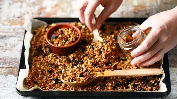Granola casera recién hecha en una bandeja para hornear. Granola en cuchara de madera y en frasco. Enfoque selectivo. Concepto de dieta saludable. Dieta cetogénica.