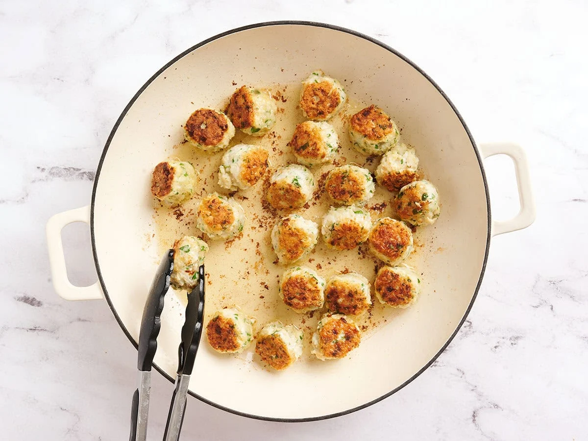 Albóndigas de pollo piccata en una sartén cocinando.