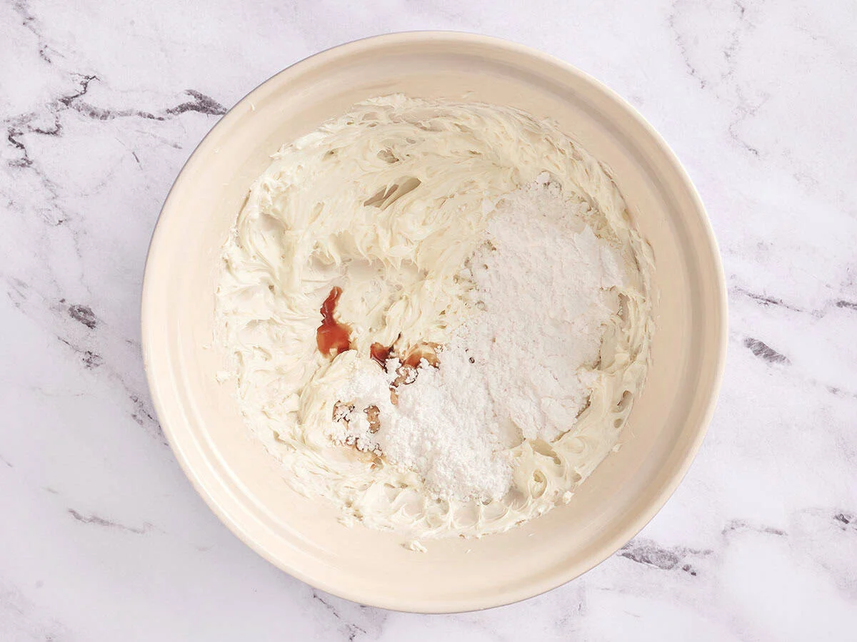 Queso crema, vainilla y azúcar glass en un bol.