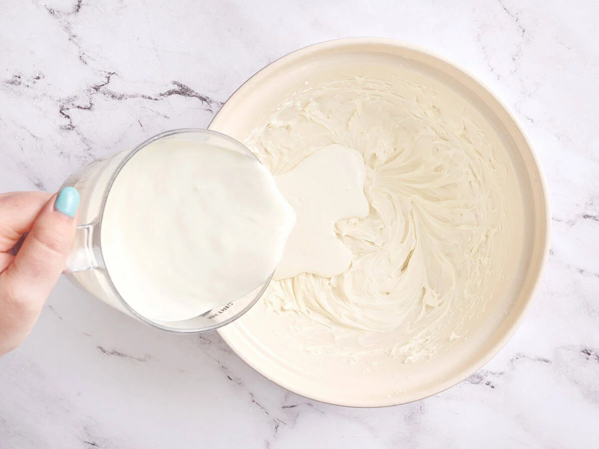 Se vierte la crema sobre queso crema batido.
