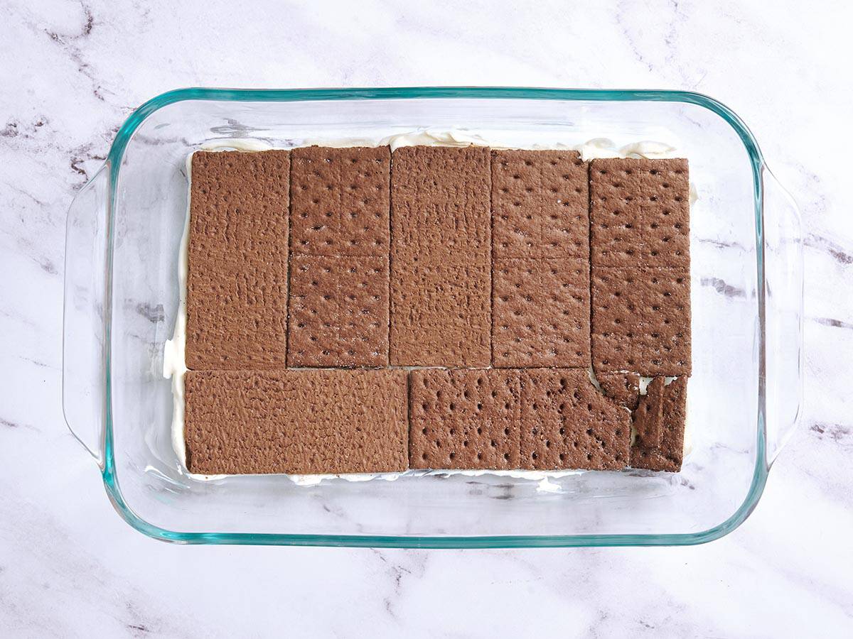 Se agrega una capa de galletas Graham de chocolate a una fuente para hornear.