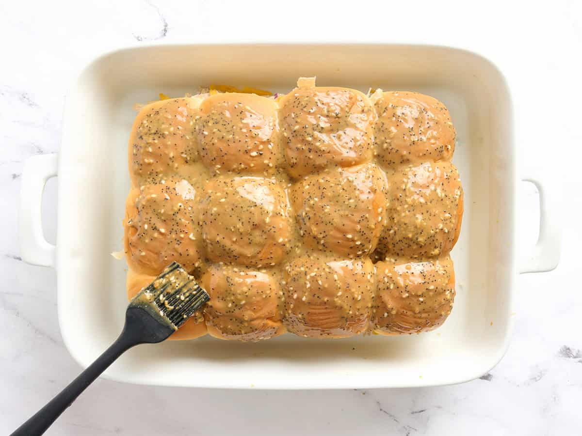 Una brocha de repostería untando las hamburguesas de pollo con una cobertura de mantequilla.