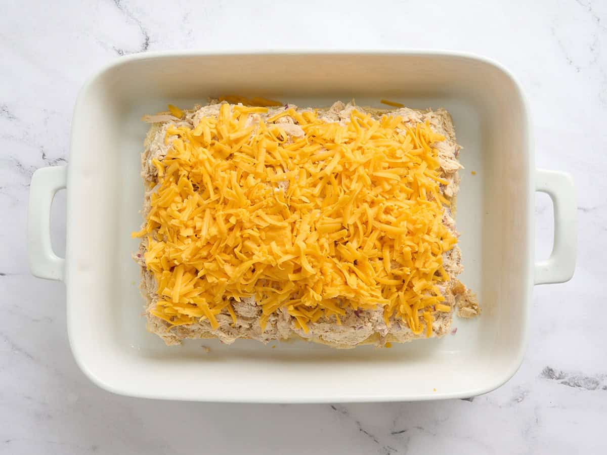 Se agregó queso cheddar rallado a las hamburguesas de pollo en una fuente para horno.