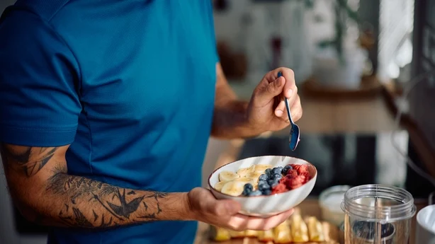 Primer plano de un hombre tomando un desayuno saludable en la cocina.