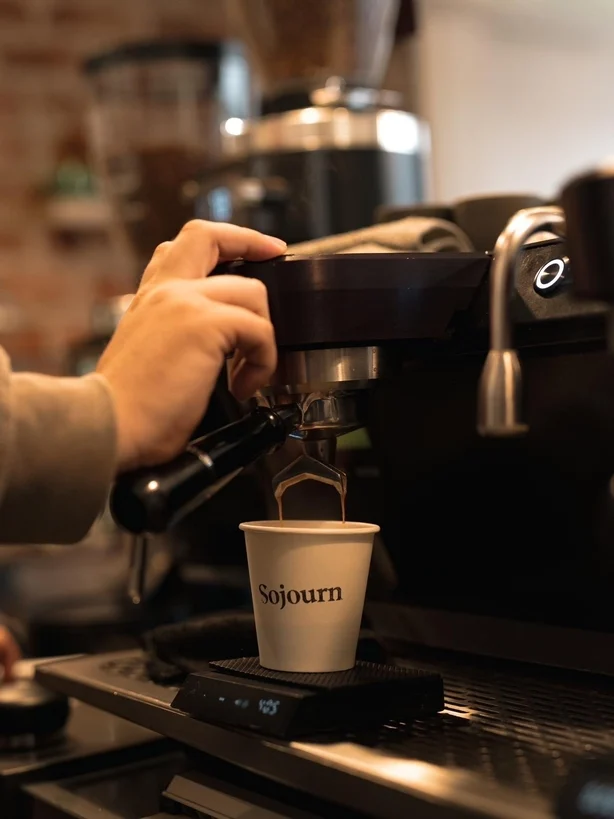Un barista tomando un trago de espresso en una máquina de café.