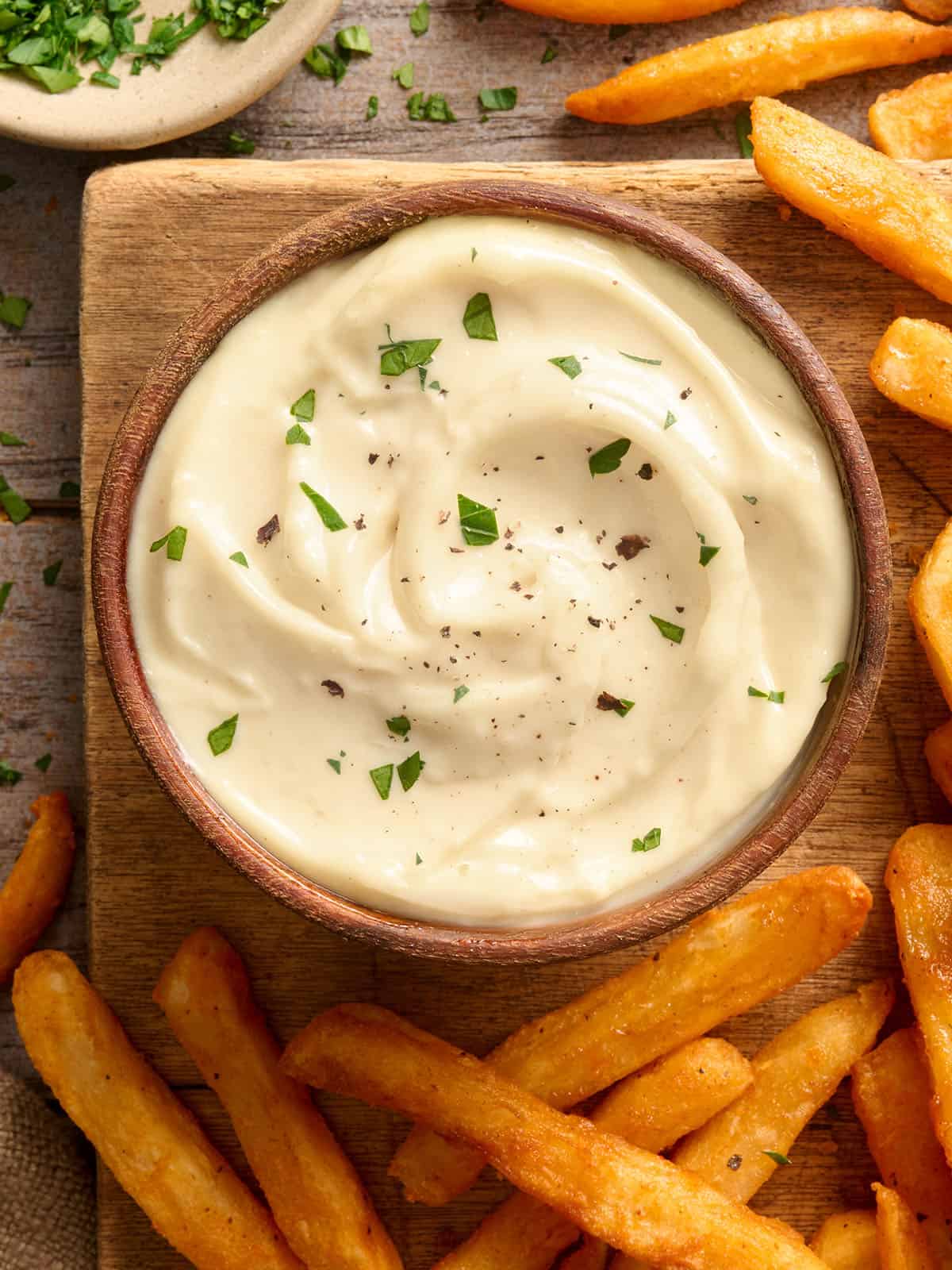 Vista aérea de un plato de alioli de ajo casero con patatas fritas.