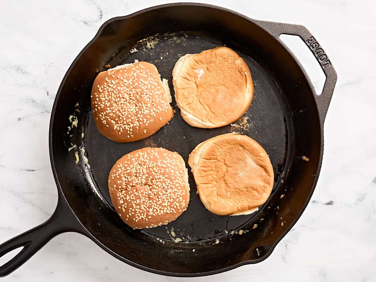 Panes de hamburguesa tostados en una sartén.