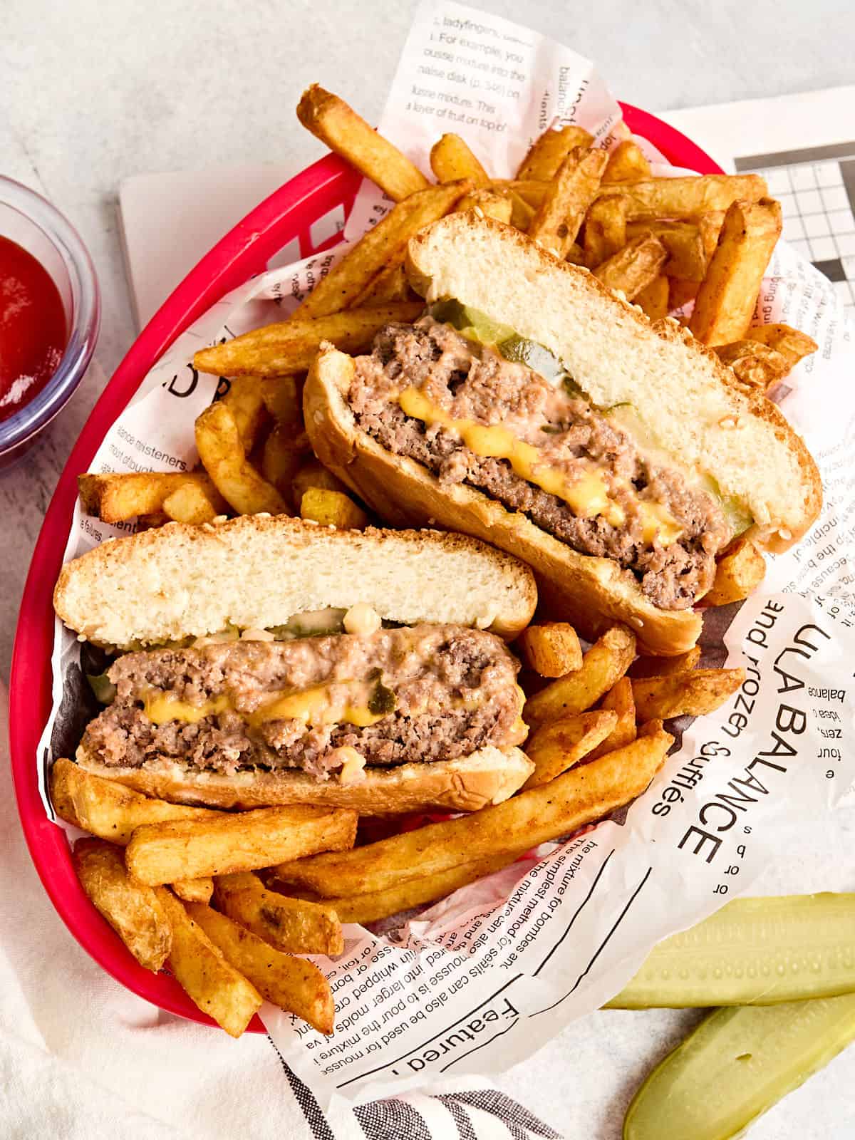 Vista aérea de una jugosa hamburguesa Lucy rellena de queso en una canasta con papas fritas.