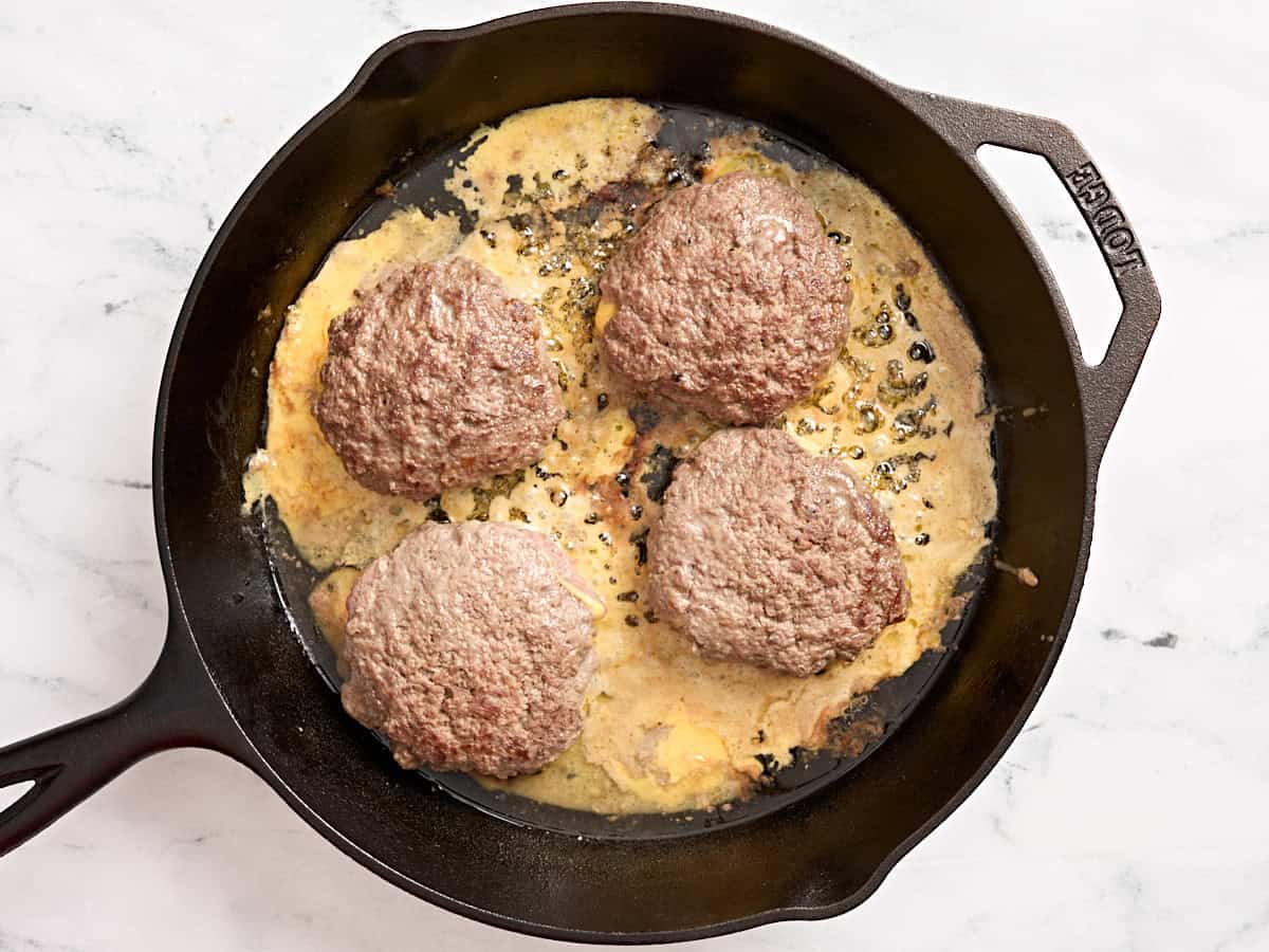 Jugosas hamburguesas Lucy cocinadas en una sartén.