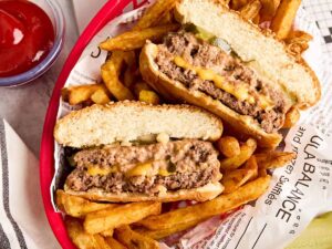 Overhead view of a cheese stuffed juicy lucy burger in a basket with fries.