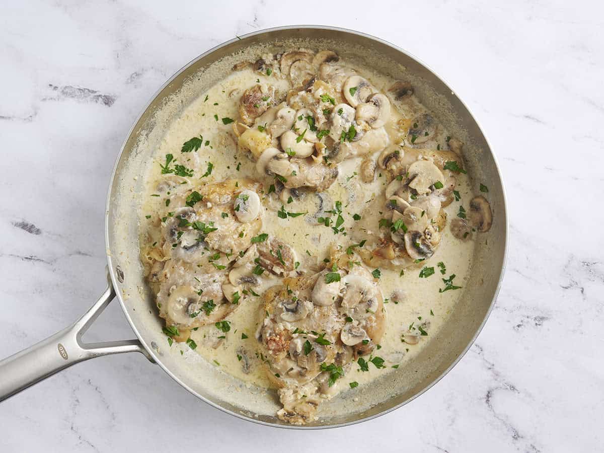 Pollo cremoso de champiñones en una sartén con perejil.